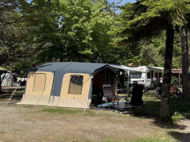 Caravan met voortent op een groene kampeerplek